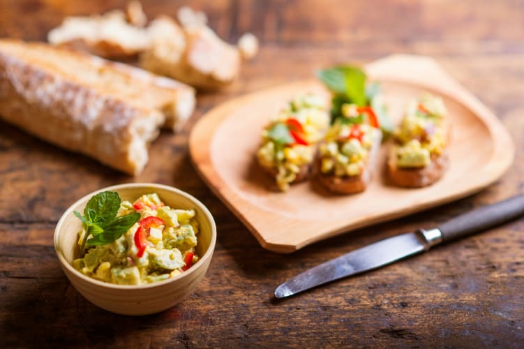 Ein leckerer Veganer Brotaufstrich aus Avocado und Paprika in einer kleinen Holzschale  