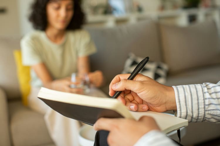 Therapiesituation in der der Therapeut etwas notiert und die Coachie auf dem Sofa sitzt