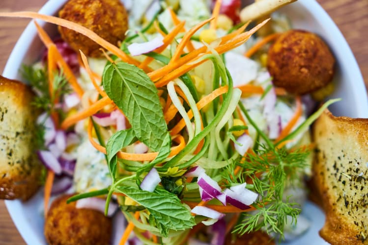 Falafel und Minzblätter auf einem Kohlsalat Engin Akyurt