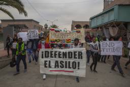 "Defiende el Asilo" "Para Título 42 Ahora," dicen pancartas en una protesta contra Título 42.
