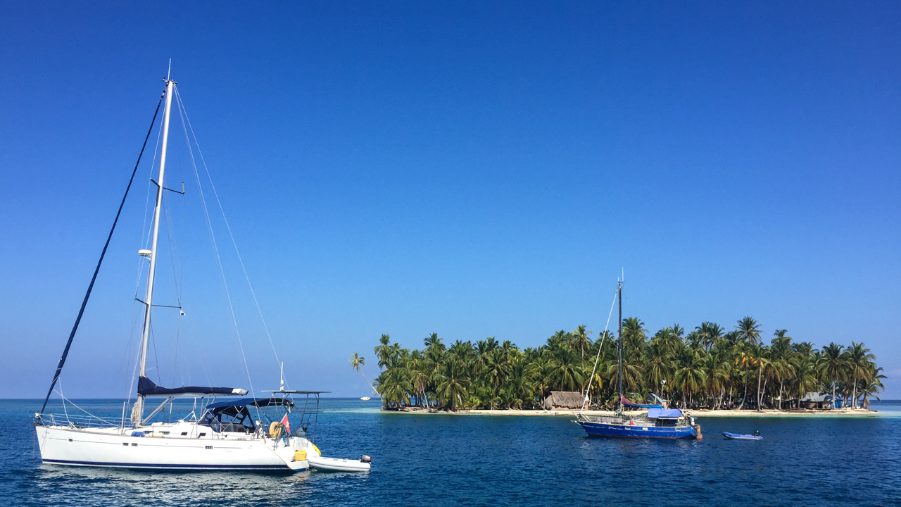 Barco a vela e pesqueiro em frente a ilha paradisíaca