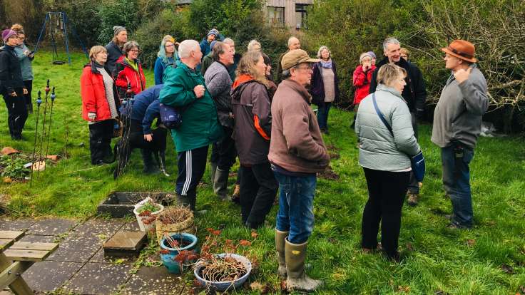 Group of people outside gathered by man talking about a tree