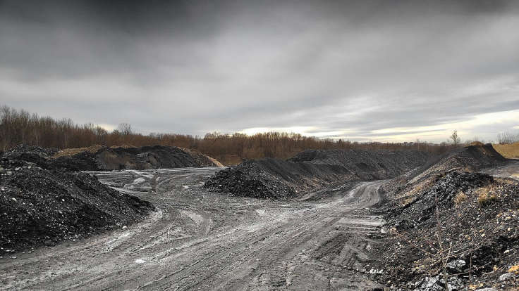 Tracks through mounds of coal slag under a grey sky