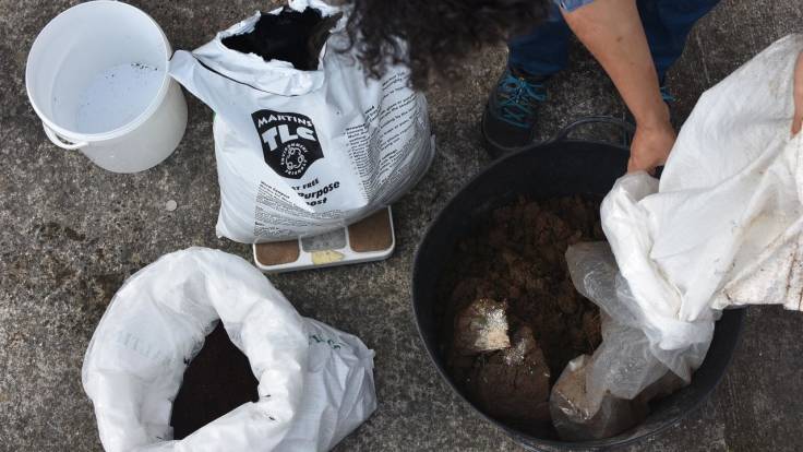 Person mixing soil in plastic bucket