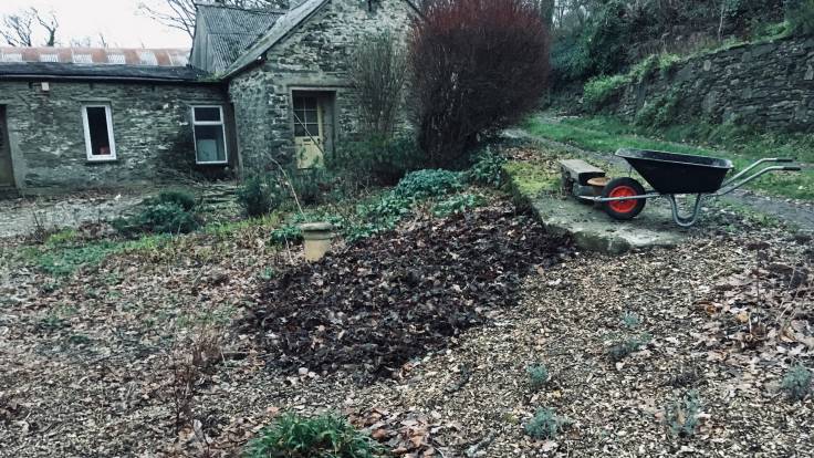 Wheelbarrow above flower bed on a slope, covered in leaf litter mulch