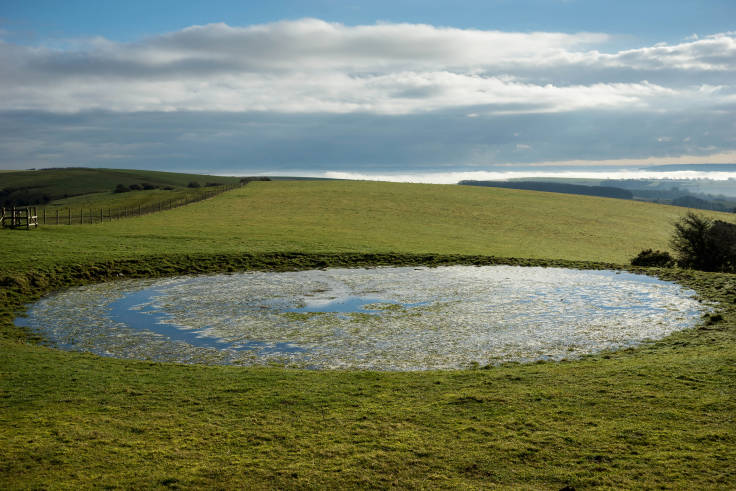 Circular pond in grass expanse hills