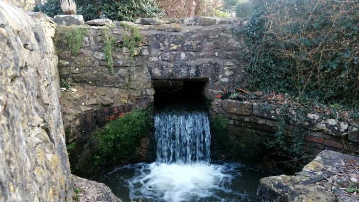 Waterfall through aperture into stone circle