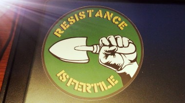 Resistance is Fertile sticker, clenched fist holding trowel, on laptop