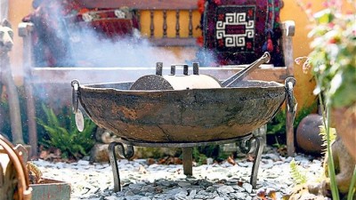 Big cast iron burning pot on legs on stone, in front of seat