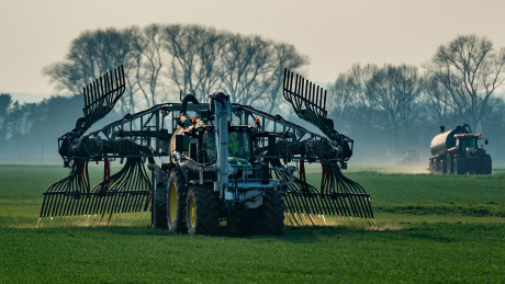 Modern tractor spreading shitty slurry over a field