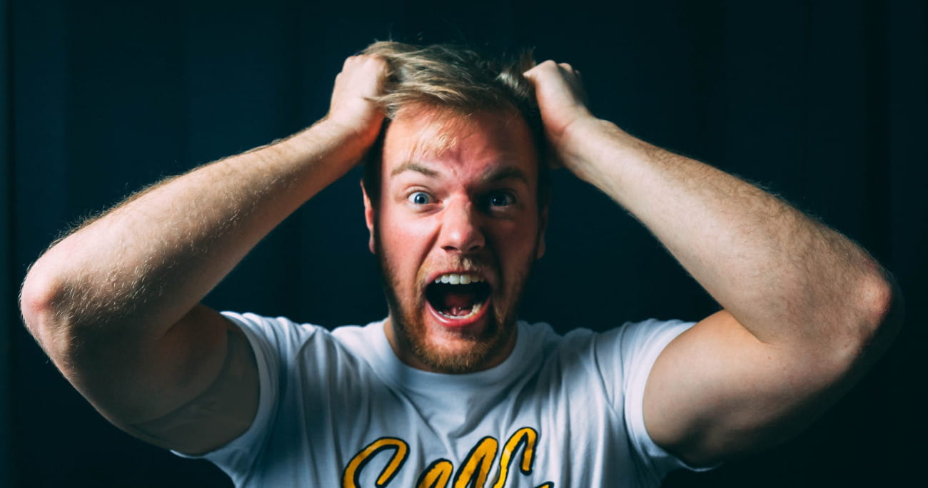 man holding his head in his hands and screaming at the camera