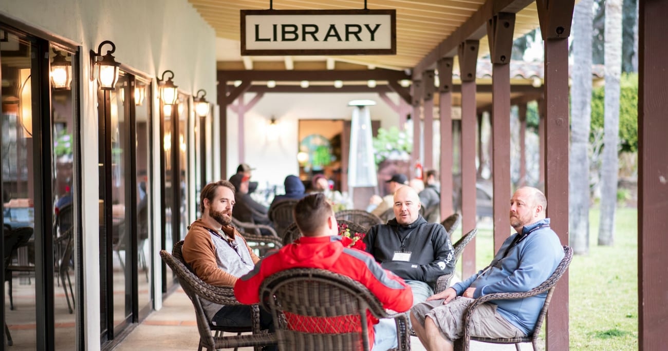A small group of men sitting outside of a library talking.