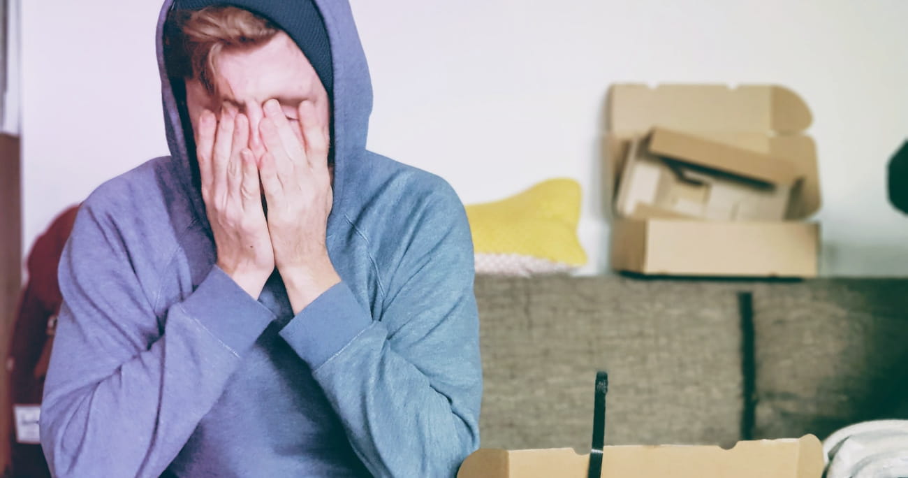 man sitting on a couch holding his face in his hands