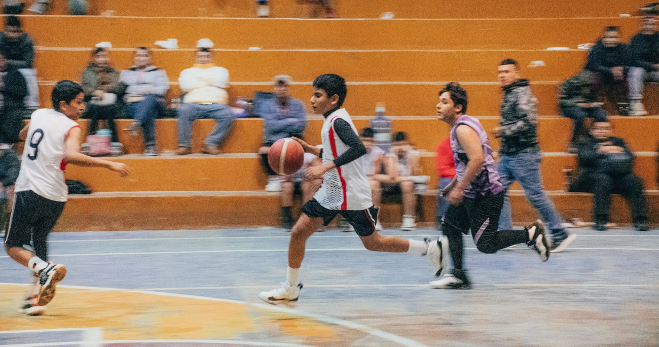 boys playing basketball with parents cheering them on