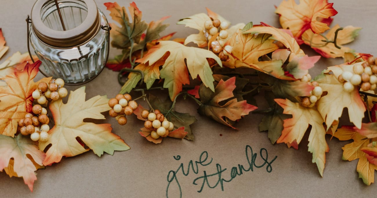 the words 'give thanks' written out on a table with fall leaves surrounding it
