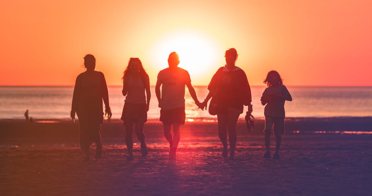 family walking on the beach during sunset