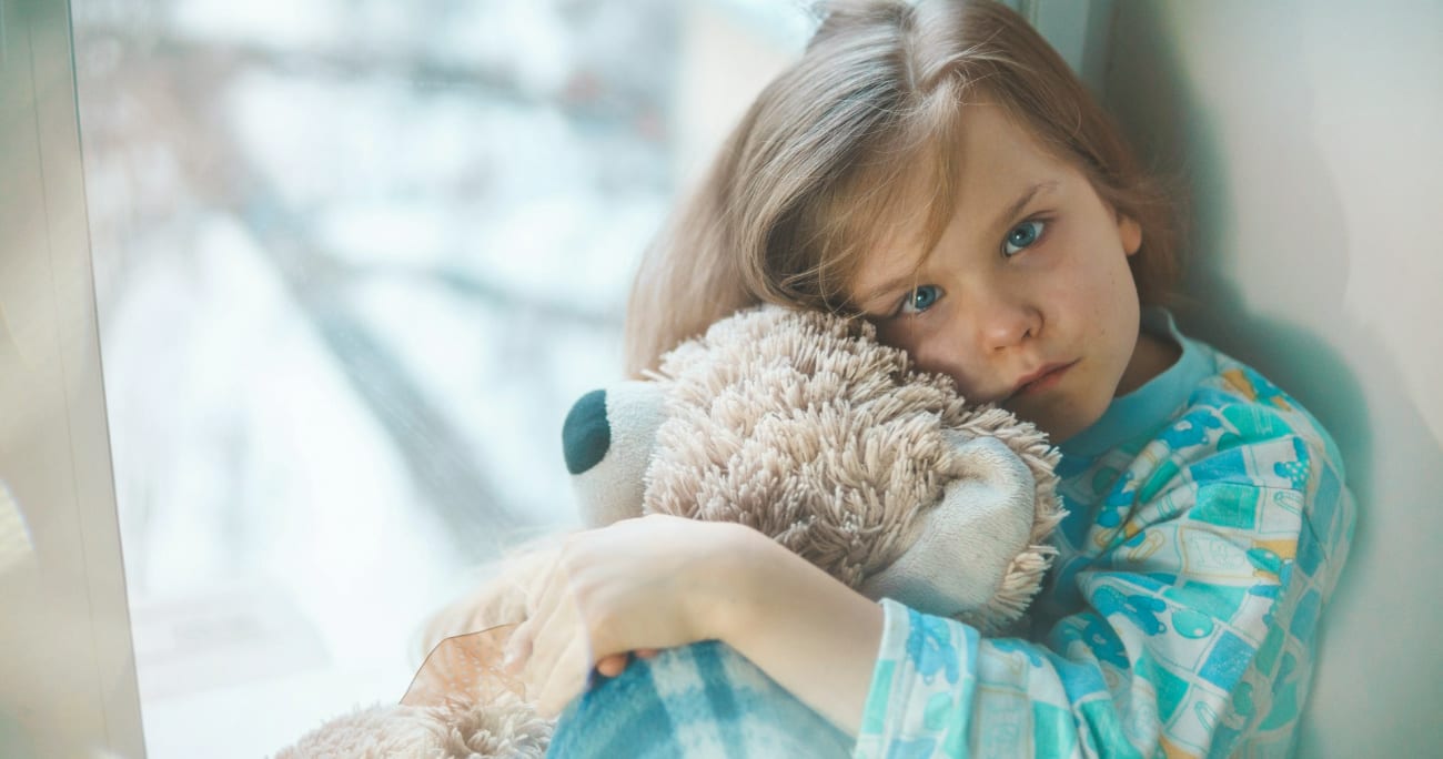 young child looking sick and holding a stuffed animal