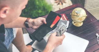 man pulling hundred dollar bills out of his wallet