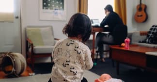 child playing in the foreground with a parent working in the background