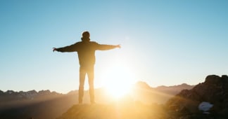man standing on a hill looking at the sunset