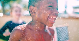 young boy playing outside in a sprinkler