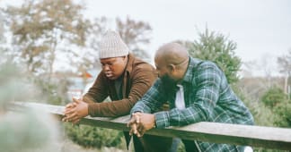 dad and son leaning on a fence and talking