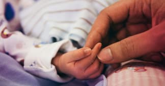 infant child’s hand holding an adult’s hand