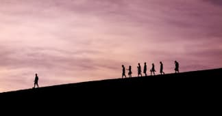 silhouette of people walking on a hill with one leading the way