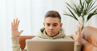 Frustrated teen using a laptop on a couch