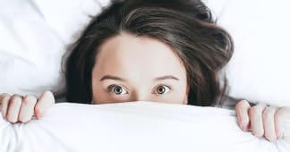 Child hiding under blankets