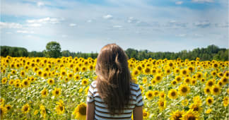 back of girl looking out over a field of sunflowers