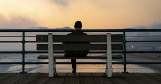 man sitting on a bench looking out over a lake