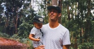 dad holding young son with forest in background
