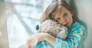 young child looking sick and holding a stuffed animal