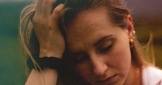 Woman looking sad and holding her hand against her forehead