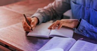 man writing down something in a notebook