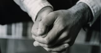 a man's hands folded in prayer