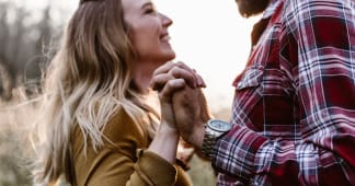 man and wife facing each other smiling and holding hands