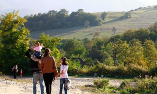 family walking in a village with a hill in the background