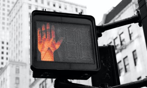 a crosswalk sign with the stop hand illuminated