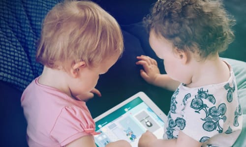 two young toddlers playing on an iPad