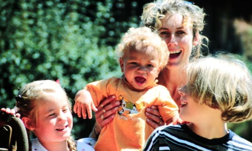 Mom with young children outside smiling and laughing