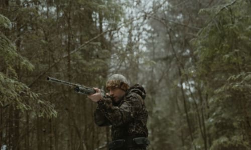 man in camo aiming a rifle in a snowy forest | Tima Miroshnichenko, via Pexels