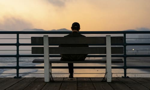 man sitting on a bench looking out over a lake