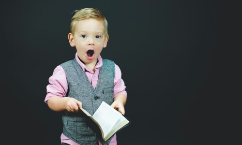 child holding a Bible with mouth open