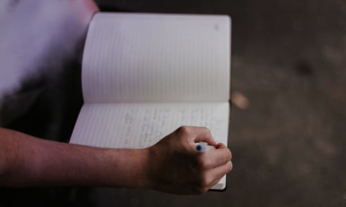 hands holding a journal and pen