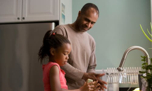 father and daughter washing dishes
