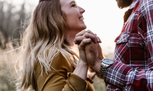 man and wife facing each other smiling and holding hands