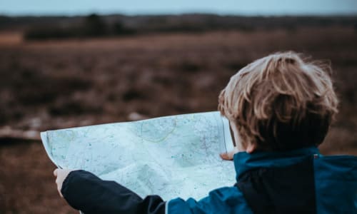child holding up map of a trail while hiking
