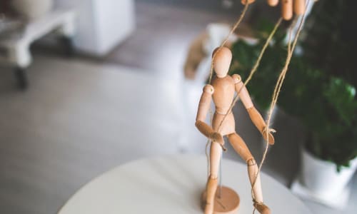 wooden marionette with strings suspended from a hand